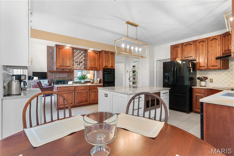 Customization abounds with two-toned cabinetry, ample quartz countertops, elegant lighting, double built-in wall ovens, a beverage center, tiled backsplash, a transome window over sink, and tile flooring — 19342 Dogwood Valley Court, Wildwood, MO 63038