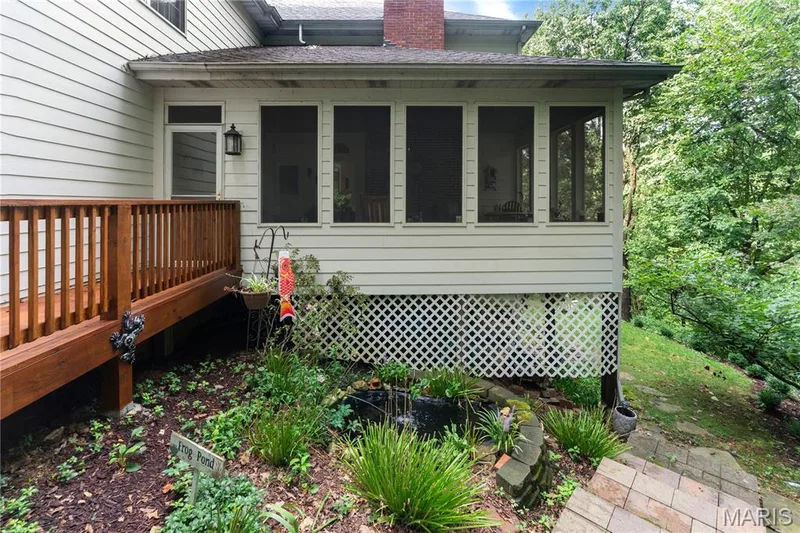 Screened-in porch with lattice skirting, wood-finish deck with railing, and stone steps — 19342 Dogwood Valley Court, Wildwood, MO 63038