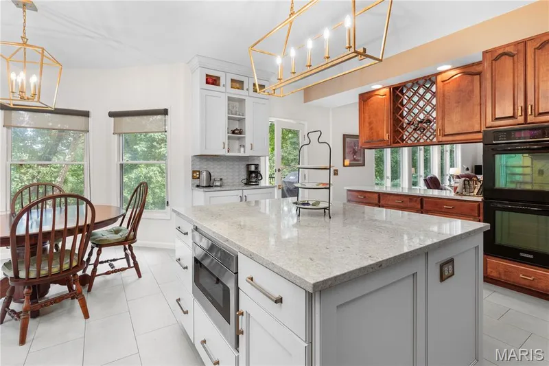 The gourmet kitchen has an oversized  central island with quartz  countertops, built-in microwave, white shaker cabinetry, and loads of storage. A cook's dream! — 19342 Dogwood Valley Court, Wildwood, MO 63038