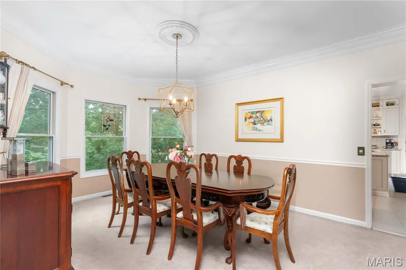 Bay window configuration with three vertical windows, crown molding, chair rail detailing, recessed geometric chandelier, and light-toned carpeting — 19342 Dogwood Valley Court, Wildwood, MO 63038