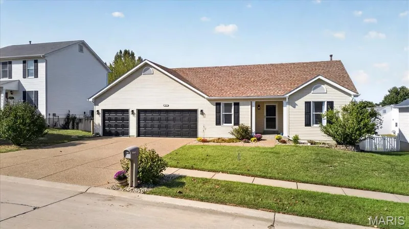 Single-story residence featuring light-colored siding, a brown shingle roof, and a two-car garage with black paneled doors — 89 Gregory Court, Wentzville, MO 63385