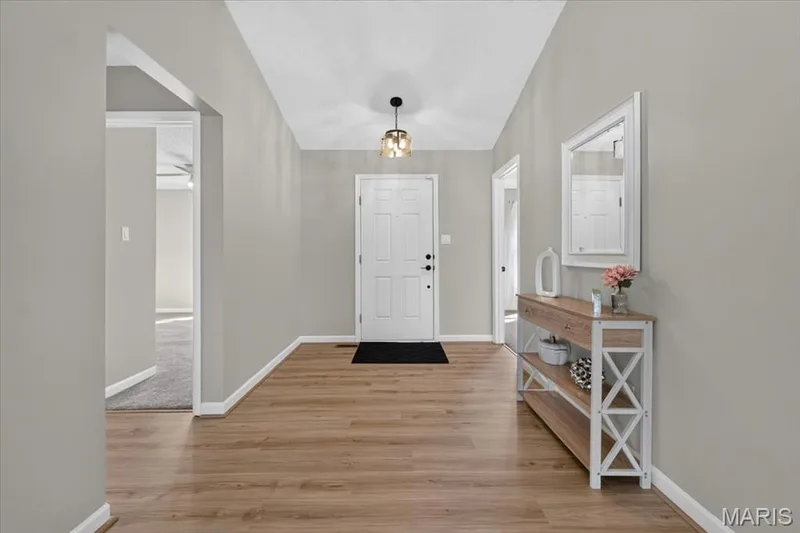 Wood-finish flooring, vaulted ceiling, neutral wall tones, white interior door, and overhead light fixture — 89 Gregory Court, Wentzville, MO 63385