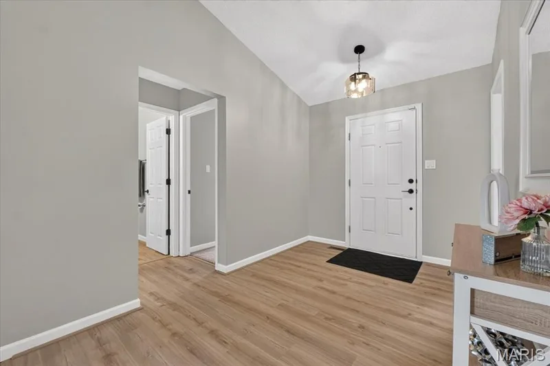 Vaulted ceiling entryway with wood-finish flooring, a contemporary ceiling light fixture, and neutral wall tones — 89 Gregory Court, Wentzville, MO 63385
