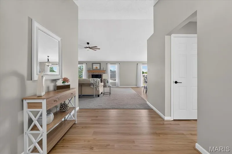 Wood-finish flooring, light gray wall tones, ceiling fan, white paneled doors, and a decorative console table — 89 Gregory Court, Wentzville, MO 63385