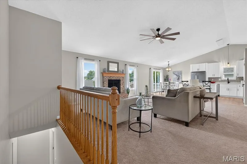 Open-concept living space with vaulted ceilings, a brick fireplace, and a ceiling fan — 89 Gregory Court, Wentzville, MO 63385