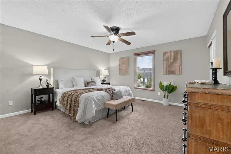 Broadloom carpeting with light gray wall tones, ceiling fan with integrated lighting, and a window featuring blinds and a wood-finish valance — 89 Gregory Court, Wentzville, MO 63385