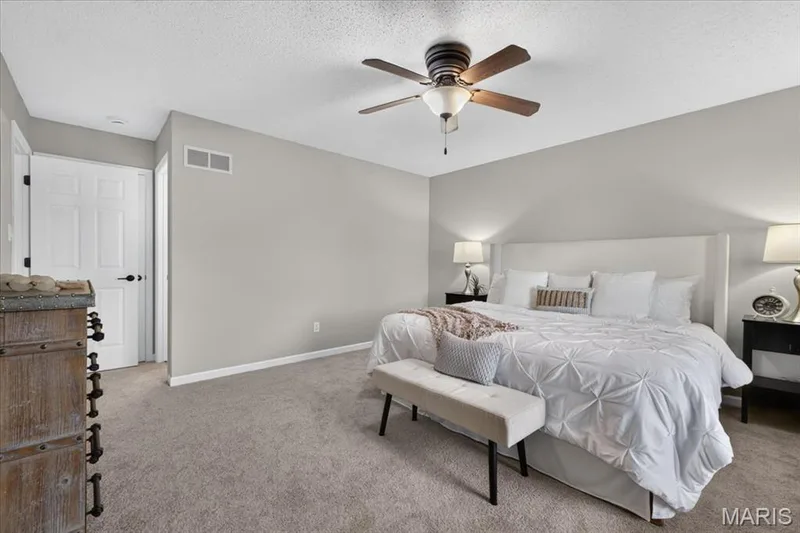 Neutral gray wall paint, textured ceiling, ceiling fan with light fixture, carpet flooring, and a white paneled door — 89 Gregory Court, Wentzville, MO 63385