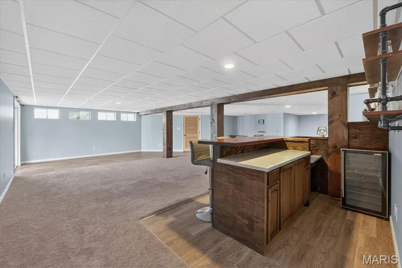 Finished lower level featuring a built-in bar with wood-finish cabinetry, a built-in beverage cooler, and wood-finish flooring — 89 Gregory Court, Wentzville, MO 63385