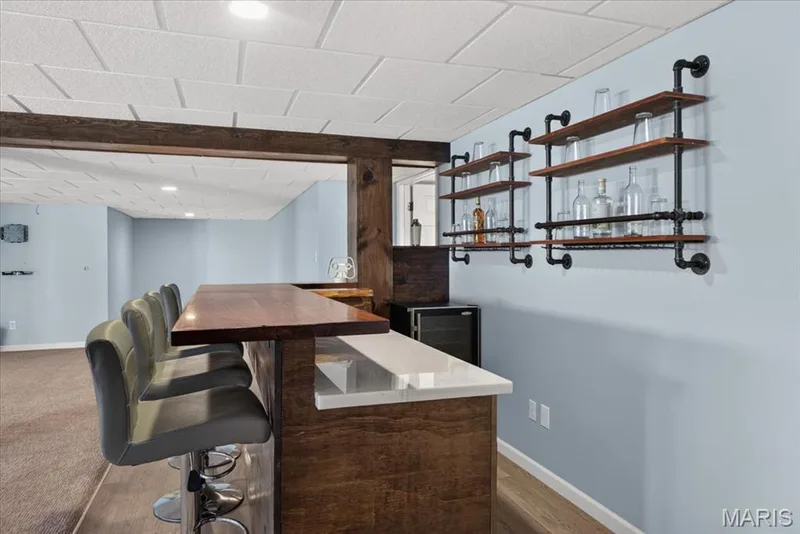 Built-in bar with wood-finish countertop, white solid surface, and integrated mini-refrigerator — 89 Gregory Court, Wentzville, MO 63385