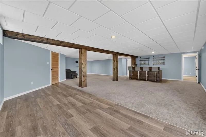 Spacious finished basement featuring wood-finish flooring, recessed lighting, and a built-in bar with bar stools — 89 Gregory Court, Wentzville, MO 63385