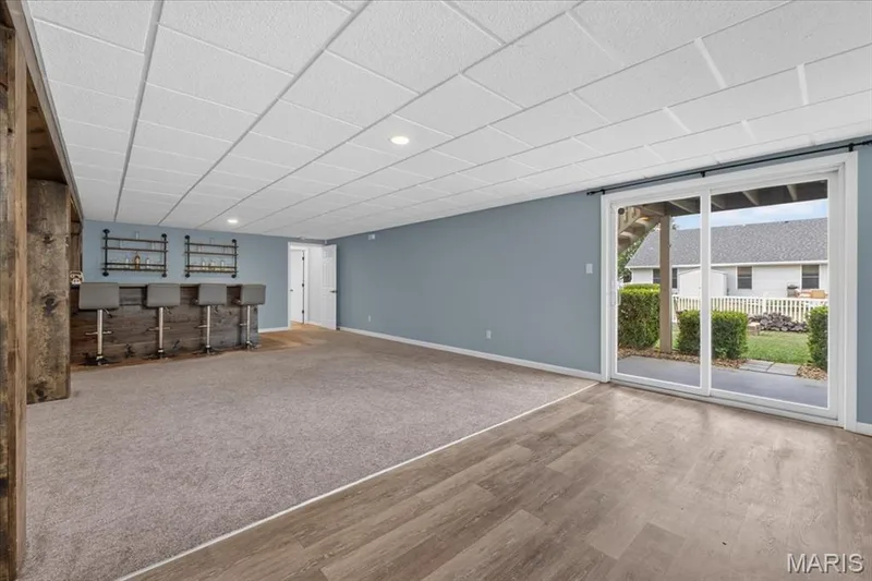 Built-in bar with wood-finish paneling, recessed lighting, wood-finish flooring, carpeted area, and sliding glass door — 89 Gregory Court, Wentzville, MO 63385