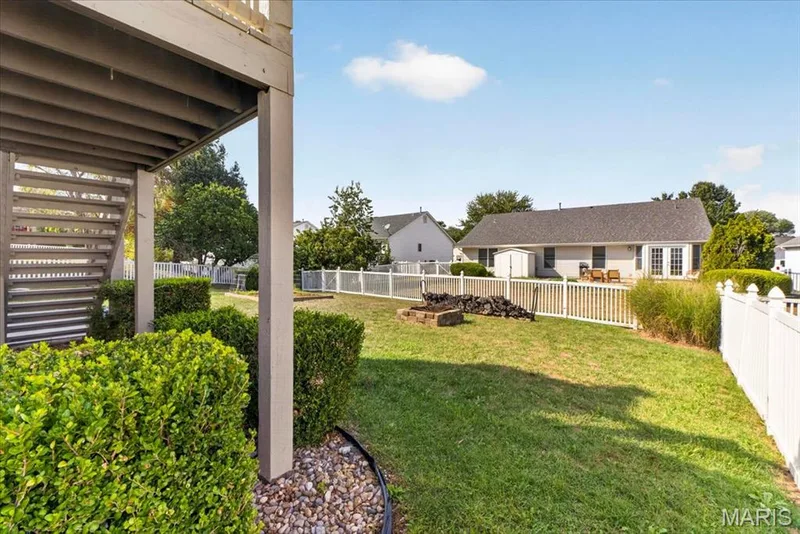 Expansive backyard with a manicured lawn, a fire pit, and white picket fencing — 89 Gregory Court, Wentzville, MO 63385