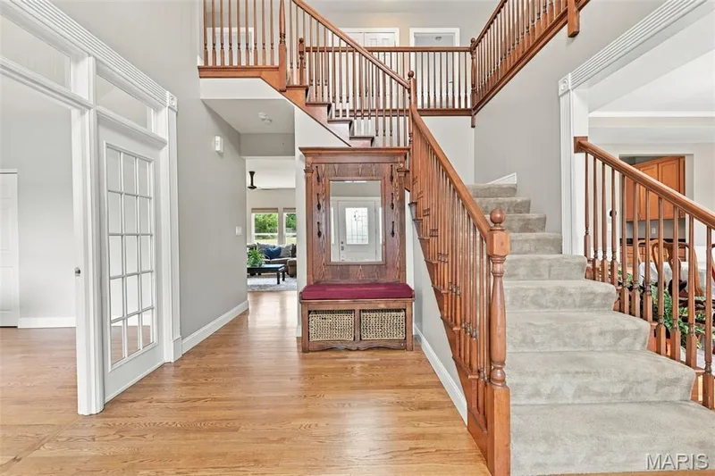 Entry with wood floors; wooden 4-foot-wide  staircase with carpeted treads — 1000 Gardenbridge Place, St Charles, MO 63303