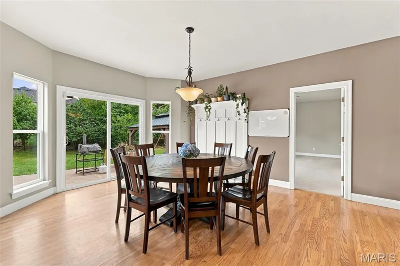 Spacious eat-in kitchen with sliding glass patio door, multiple windows, built-in wall unit with hooks and shelving, and a decorative pendant light fixture — 1000 Gardenbridge Place, St Charles, MO 63303