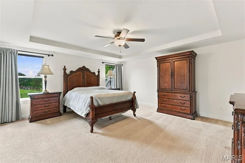 Large bedroom has recessed ceiling, dual windows, ceiling fan, and carpeted floor — 1000 Gardenbridge Place, St Charles, MO 63303