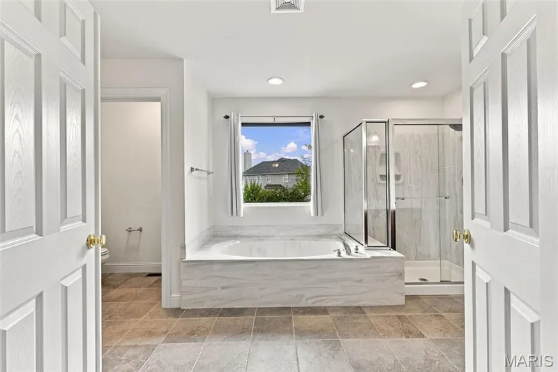 Soaking tub with a marble-finish surround, tile floor, glass-enclosed shower, and recessed lighting — 1000 Gardenbridge Place, St Charles, MO 63303