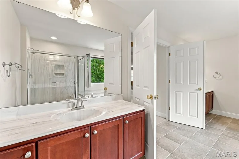 Dual-sink vanity with a light-toned countertop, wood cabinetry — 1000 Gardenbridge Place, St Charles, MO 63303