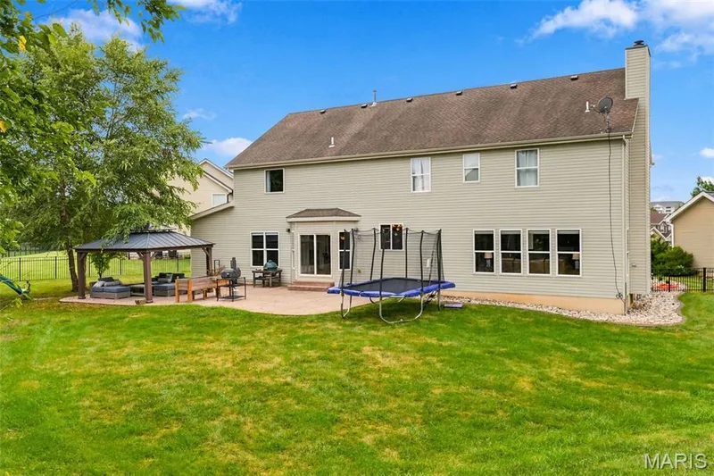 Spacious backyard featuring a stamped, paved patio with gazebo, mature trees, and fenced-in backyard — 1000 Gardenbridge Place, St Charles, MO 63303