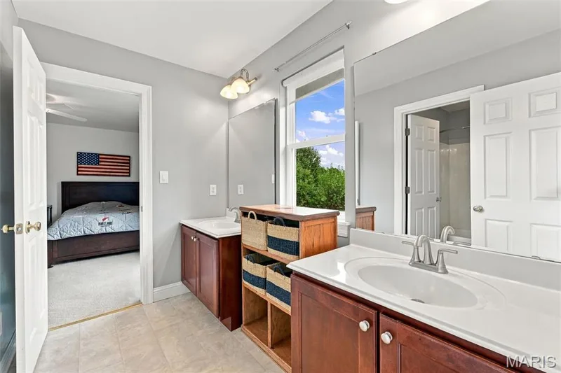 Jack n' Jill bathroom has dual vanity, wood-finish cabinetry, and neutral countertops — 1000 Gardenbridge Place, St Charles, MO 63303
