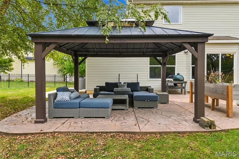 Rear patio featuring a covered gazebo, stamped concrete surface, and raised garden beds — 1000 Gardenbridge Place, St Charles, MO 63303