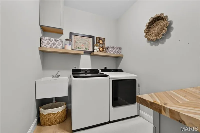 laundry room across from drop zone w/ utility sink and cabinets w/ golding table and hang bar — 512 Spruce Hollow Court, Wentzville, MO 63385
