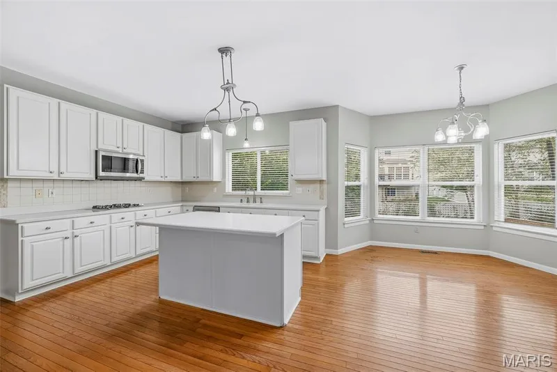 Island with Seating Bar, Solid Surface Countertops, Tile Backsplash and Stainless Steel Appliances in Kitchen — 223 Chestnut Hill Drive, O'Fallon, MO 63368