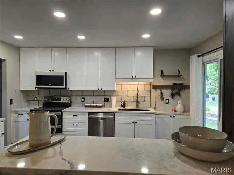 Kitchen with white cabinets, granite countertops and newer appliances — 266 Savoy Drive, Lake St. Louis, MO 63367