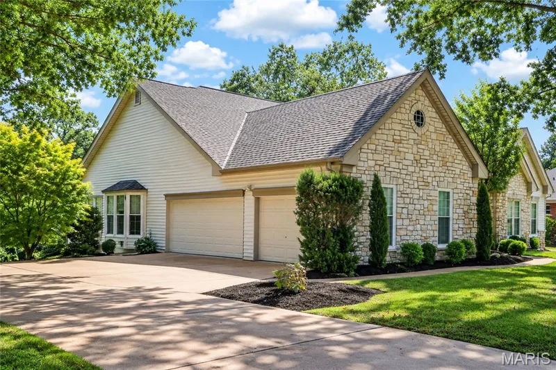 Stone and siding exterior with a multi-car garage, mature landscaping, bay window, and a gabled roof — 17711 Birch Leaf Court, Chesterfield, MO 63005
