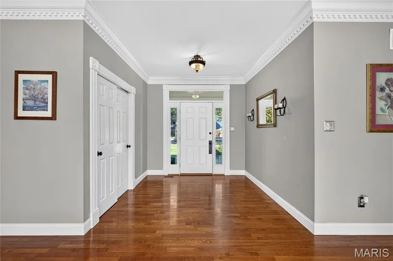 Hardwood flooring, decorative crown molding, white trim work, transom window, and a central ceiling light fixture — 17711 Birch Leaf Court, Chesterfield, MO 63005
