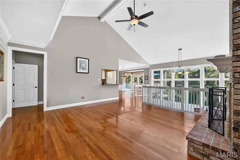 Wood-finish flooring, vaulted ceiling, exposed beams, ceiling fan, and a brick fireplace — 17711 Birch Leaf Court, Chesterfield, MO 63005