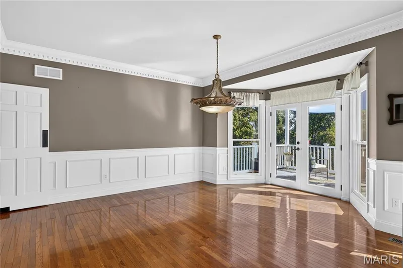 Hardwood flooring, decorative crown molding, wainscoting, and French doors leading to an exterior balcony — 17711 Birch Leaf Court, Chesterfield, MO 63005