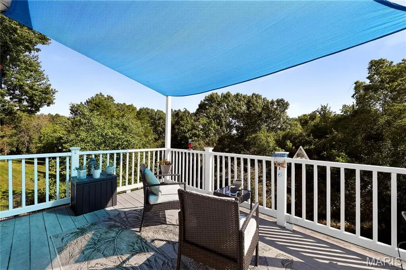 Outdoor deck featuring a blue shade sail, white railing, and wood-finish decking — 17711 Birch Leaf Court, Chesterfield, MO 63005