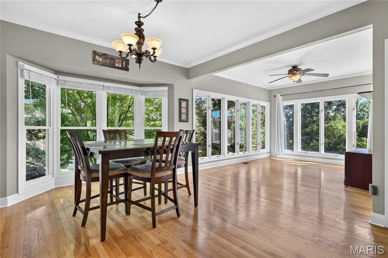 Hardwood flooring throughout, a bay window, recessed ceiling with crown molding, a decorative ceiling fan, and a chandelier — 17711 Birch Leaf Court, Chesterfield, MO 63005