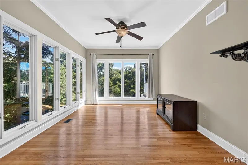 Hardwood flooring, crown molding, a ceiling fan, and large windows with white trim — 17711 Birch Leaf Court, Chesterfield, MO 63005