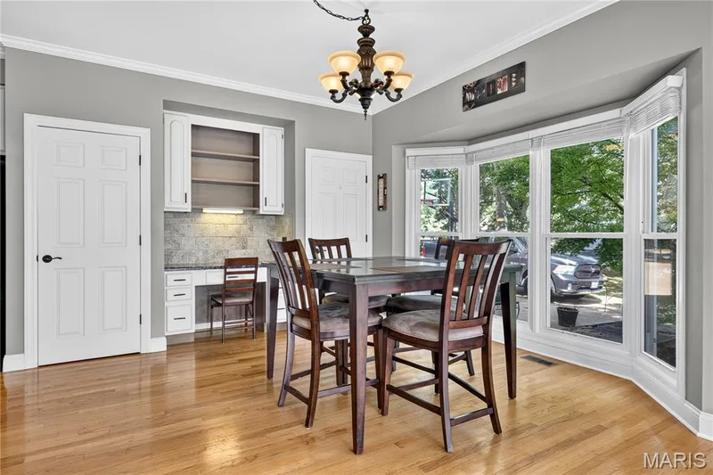 Hardwood flooring, built-in desk with overhead cabinetry, bay window, chandelier light fixture, and crown molding — 17711 Birch Leaf Court, Chesterfield, MO 63005