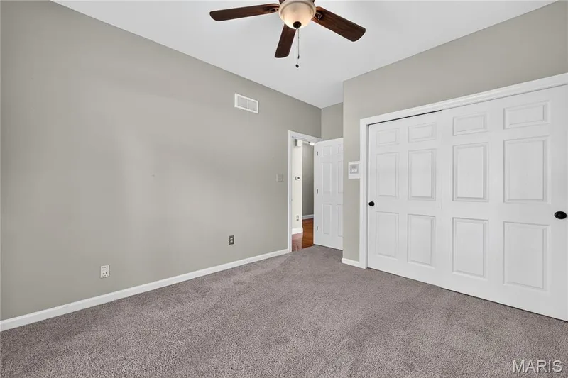 Neutral wall paint, ceiling fan, gray carpet, paneled bifold closet doors, and white trim — 17711 Birch Leaf Court, Chesterfield, MO 63005