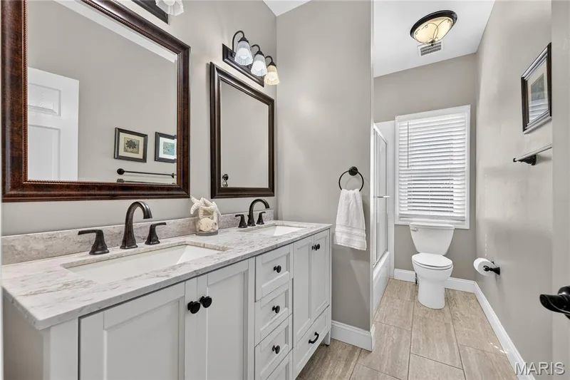 Dual vanity with undermount sinks, bronze finish hardware, and a light-toned countertop — 17711 Birch Leaf Court, Chesterfield, MO 63005