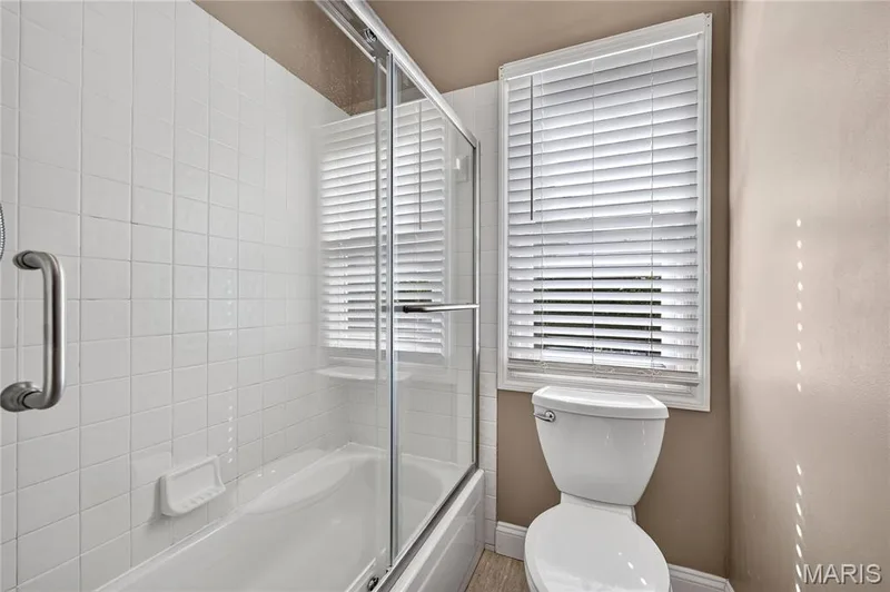 Bathtub with white tile surround and clear glass shower enclosure — 17711 Birch Leaf Court, Chesterfield, MO 63005
