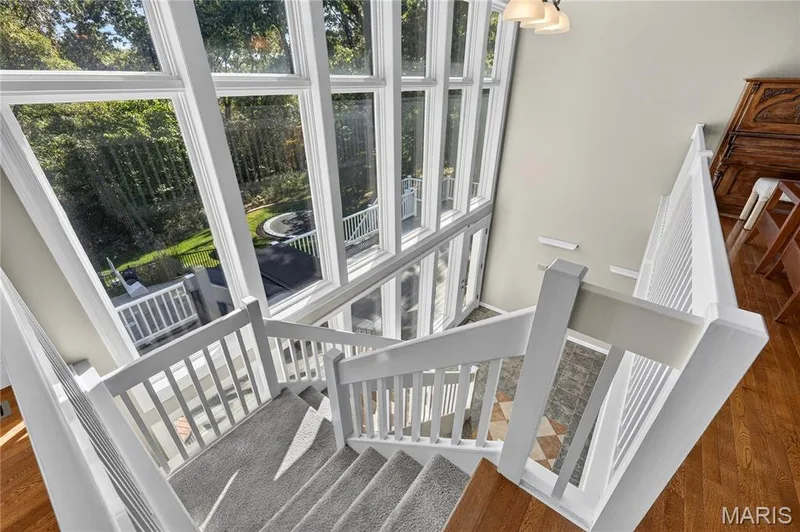 Multi-level staircase with white balusters, carpeted treads, and hardwood flooring — 17711 Birch Leaf Court, Chesterfield, MO 63005