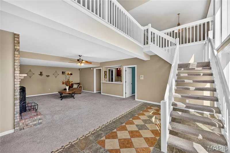 Open-concept living area featuring a brick fireplace, carpeted flooring, and a ceiling fan — 17711 Birch Leaf Court, Chesterfield, MO 63005