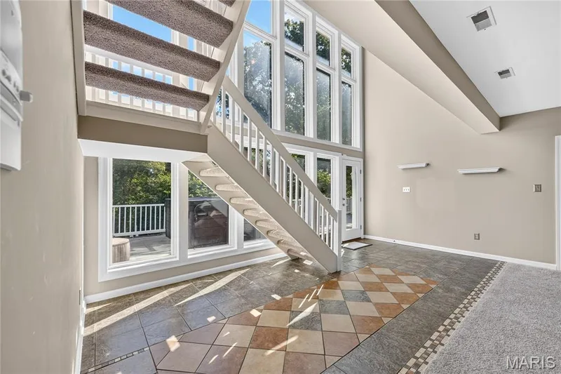 Two-story vaulted ceiling with recessed lighting, full-height windows, a glass-paneled door, and a staircase with carpeted treads — 17711 Birch Leaf Court, Chesterfield, MO 63005