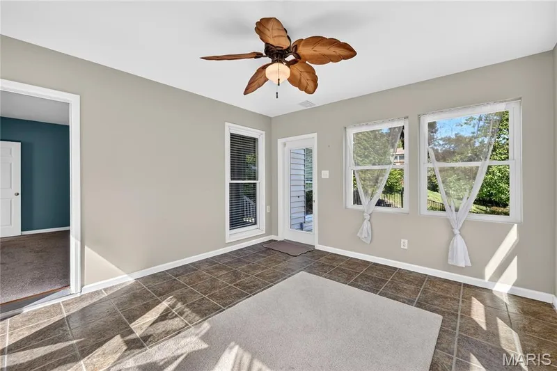 Tiled flooring, ceiling fan with integrated lighting, multiple windows, and a glass-paneled door — 17711 Birch Leaf Court, Chesterfield, MO 63005