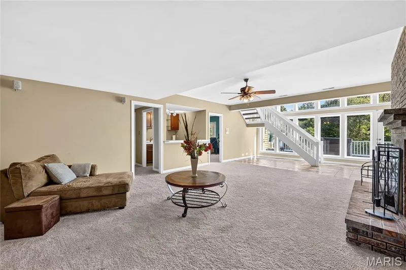 Expansive living area with a floor-to-ceiling brick fireplace, large picture windows, and a built-in staircase — 17711 Birch Leaf Court, Chesterfield, MO 63005