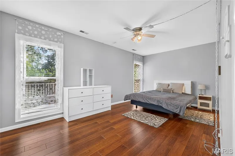 Hardwood flooring, painted walls, ceiling fan with integrated lighting, and multiple windows — 17711 Birch Leaf Court, Chesterfield, MO 63005