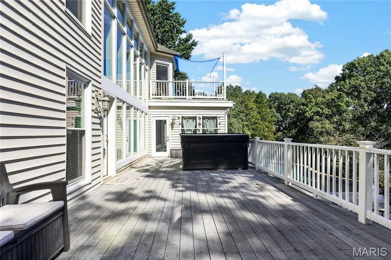 Expansive outdoor decking with a built-in hot tub, white railing, and multiple access points to the residence — 17711 Birch Leaf Court, Chesterfield, MO 63005