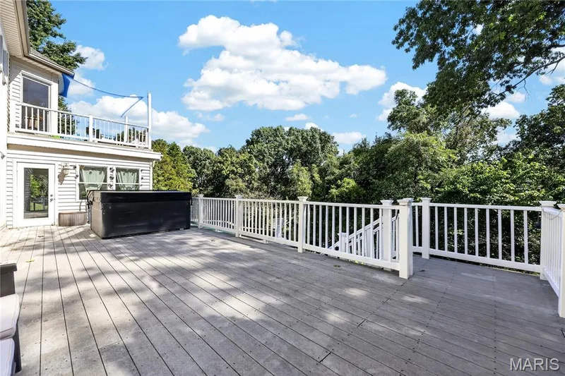 Expansive multi-level wood-finish deck with white railings, featuring a built-in hot tub and direct access to the upper and lower levels of the residence — 17711 Birch Leaf Court, Chesterfield, MO 63005