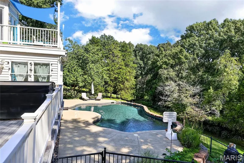 Outdoor swimming pool with concrete surround, multi-level deck, white railing, and lush perimeter landscaping — 17711 Birch Leaf Court, Chesterfield, MO 63005