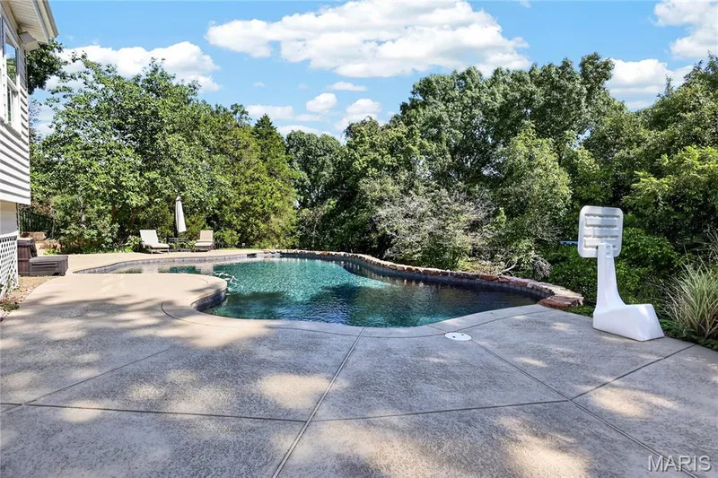 Irregular-shaped swimming pool with surrounding concrete decking — 17711 Birch Leaf Court, Chesterfield, MO 63005