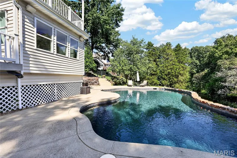 Curved swimming pool with stone coping and concrete surround — 17711 Birch Leaf Court, Chesterfield, MO 63005