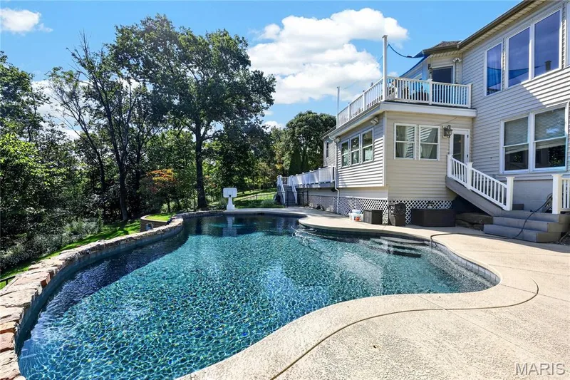 Curved swimming pool with stone-clad retaining wall and concrete decking — 17711 Birch Leaf Court, Chesterfield, MO 63005